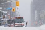 Um pedestre atravessa a rua enquanto um ônibus da cidade é flagrado preso durante uma tempestade de inverno em Toronto na segunda-feira, 17 de janeiro de 2022. 