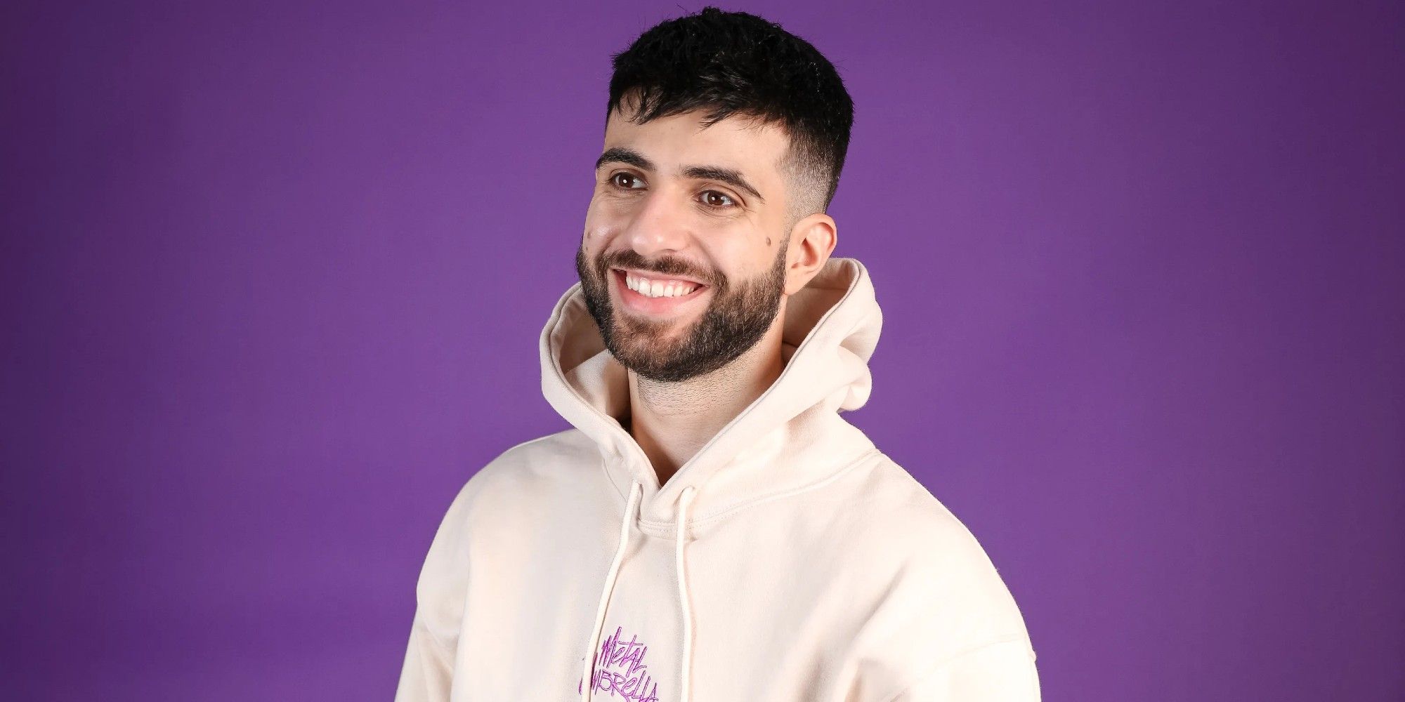sypherpk sorrindo em frente a uma parede roxa