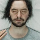 Dylan asleep with a hand touching his shoulder during the trailer for Control 2.